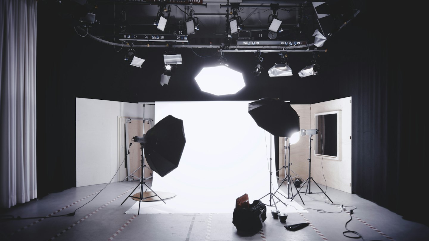 Heller Fotostudio mit nahtlosem weißem Hintergrund und Beleuchtungsausrüstung.